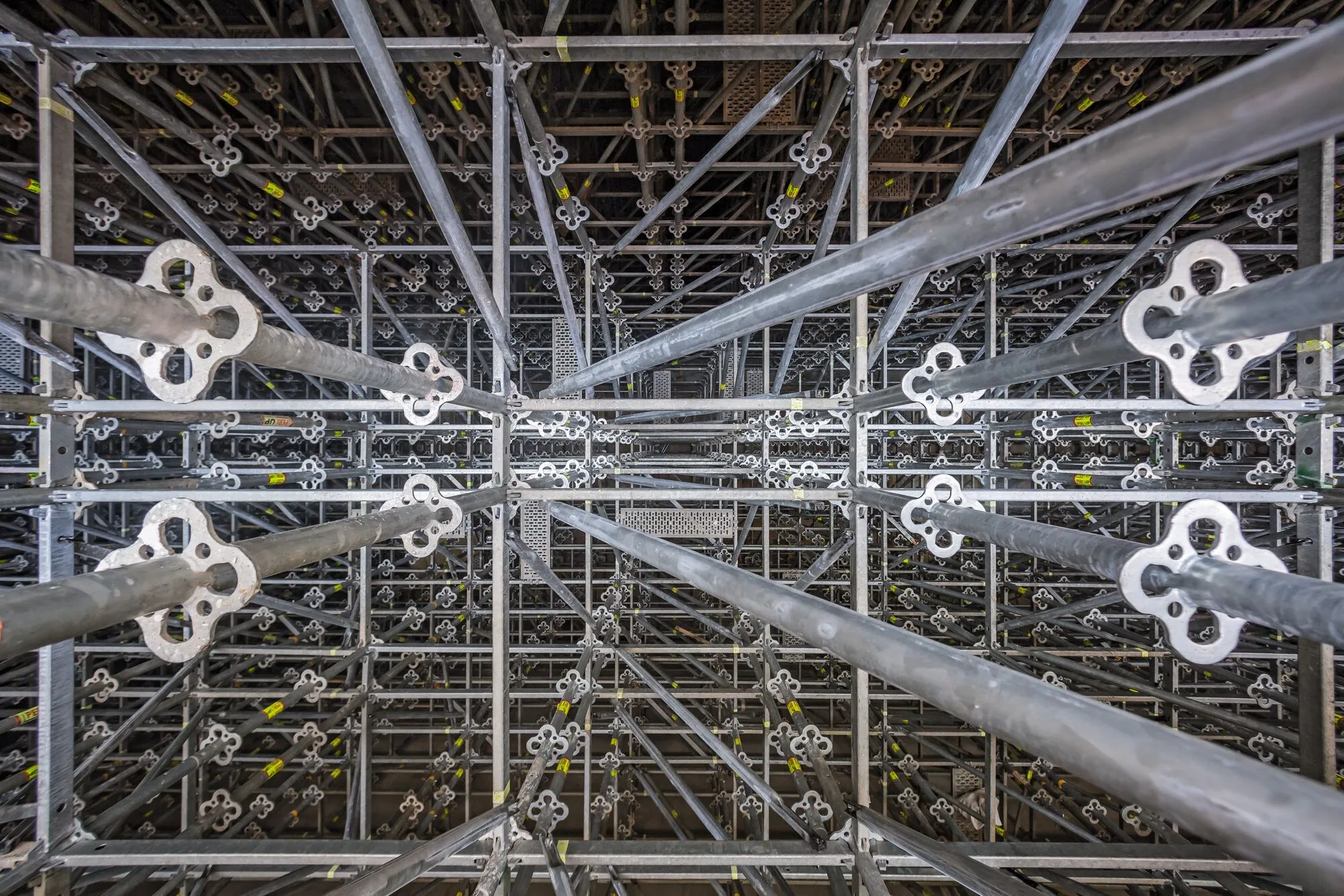 Metallinen rakennusteline, jossa on toistuvia neliapilan muotoisia liittimiä ja harmaita tukipalkkeja, valaistus on tasainen ja kirkas.